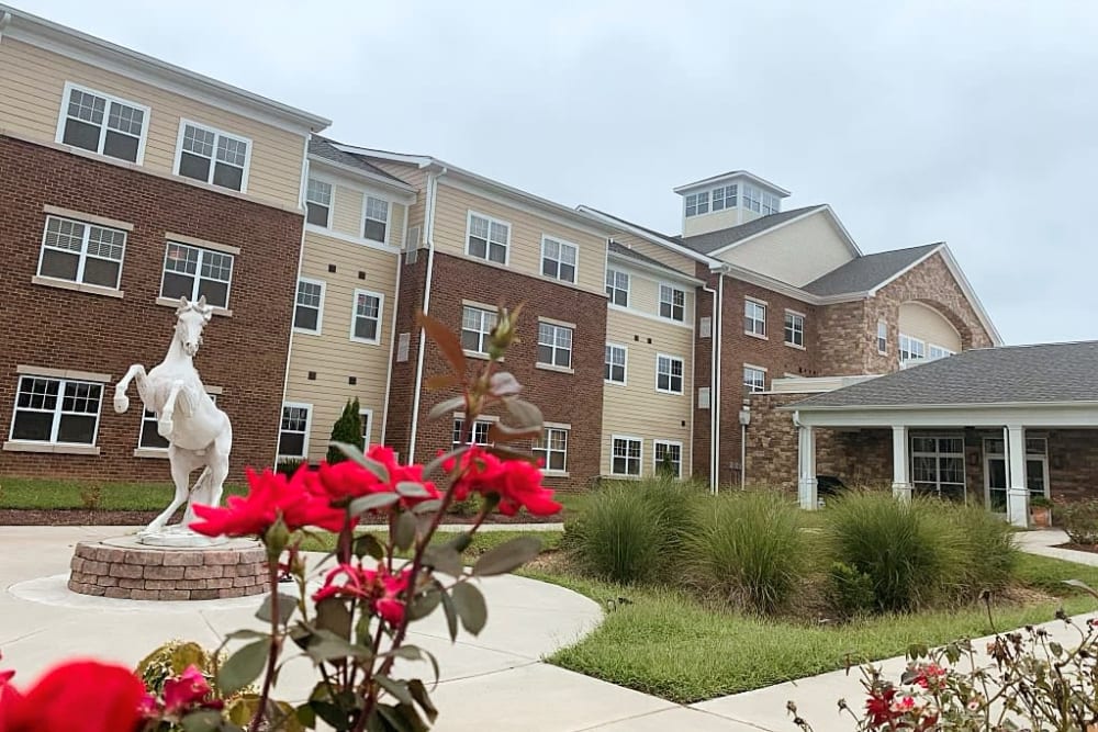 The building entrance adorned with vibrant flowers and a prominent statue, inviting visitors with its charm.